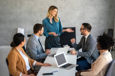 Çok ırklı başarılı iş adamları, analitik rapor sunan profesyoneller modern ofisteki meslektaşlarıyla birlikte çalışıyorlar.