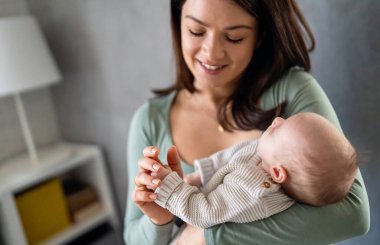 Sevgi dolu bir anne, yeni doğmuş bebeğini evde taşıyor. Mutlu bir annenin parlak portresi. Elinde uyuyan bir bebeği tutuyor..