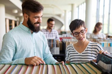 Öğrenciler kütüphanede okuyor. Gençler birlikte zaman geçirip birlikte öğreniyor..