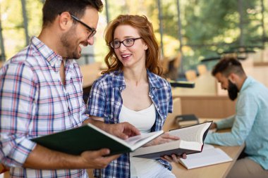 Bir üniversite kütüphanesinde birlikte çalışan mutlu bir öğrenci grubu. Eğitim insanları takım çalışması kavramı.