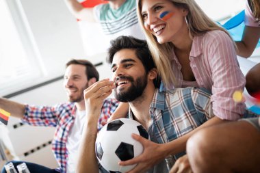 Spor fanatiklerinin çeşitli karışımları maç kazanma maçlarını televizyonda izleyip galibiyet golünü kutluyor.