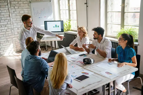 Business professionals. Group of young confident happy business people analyzing data during meeting in the office