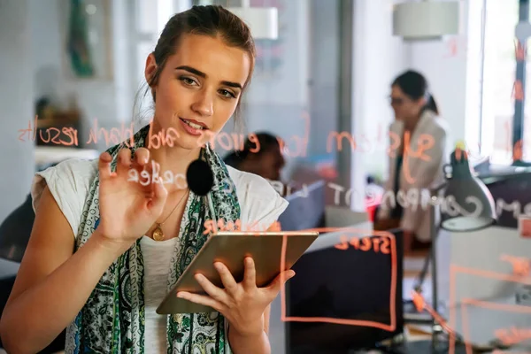 在工作场所的工作间 妇女在玻璃上写字 在启动项目的工作流程规划战略中记录信息 — 图库照片