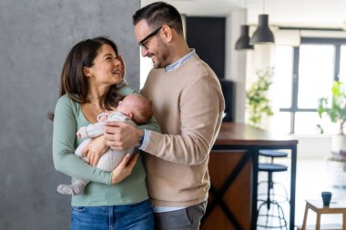 Mutlu bir genç adam ve kadın holding yeni doğan şirin bebek portre beyaz unisex kılığına girmiş. Beyaz gülümseyen baba ve anne kucaklayan şefkatle çok güzel yeni doğan çocuk. Mutlu aile kavramı