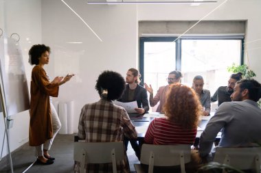 Ofisteki çeşitli çalışanlar yeni projeleri için yeni fikirleri tartışırken beyin fırtınası sırasında eğleniyorlar. Yönetim kurulundaki çok ırklı iş arkadaşları brifingde fikir alışverişinde bulundular..