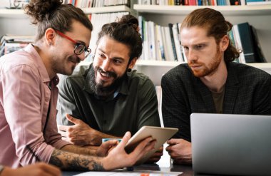 Mixed team of software engineers brainstorming ideas for new code library in front of computer screens compiling algorithms. Diverse app developers collaborating on group project in it agency office.