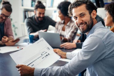 Gülümseyen çeşitli meslektaşlar toplantı odasında toplanmış mali istatistikleri tartışıyorlar. Mutlu çok ırklı iş arkadaşları ofis toplantılarında işbirliği yaparken eğleniyorlar. Takım çalışması konsepti.