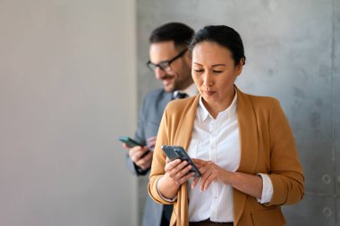 Ofisteki Orta yaşlı Asyalı iş kadını. Başarılı bir kadın cep telefonuyla mesaj atıyor ve çalışıyor. Gülümseyen iş kadını.