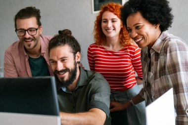Mixed team of software engineers brainstorming ideas for new code library in front of computer screens compiling algorithms. Diverse app developers collaborating on group project in it agency office.