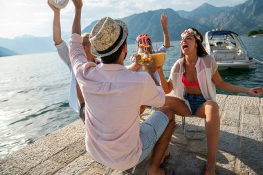 Mutlu gençler plaj partisinde eğleniyor. Bir grup arkadaş yaz tatilinin ve seyahatin tadını çıkarıyor