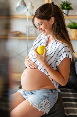 Hamilelik, sağlıklı yiyecekler ve elma yiyen genç hamile kadın kavramı. sağlıklı yiyecekler.