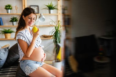 Hamilelik boyunca beslenme ve diyet. Hamile genç bir kadın sağlıklı gıda ve vitaminlere dikkat eder.