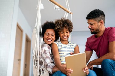 Mutlu Afrikalı aile evde cihazla eğleniyor, siyahi ebeveynler ve çocuk dijital tablet kullanıyorlar ve birlikte ekrana bakıyorlar.