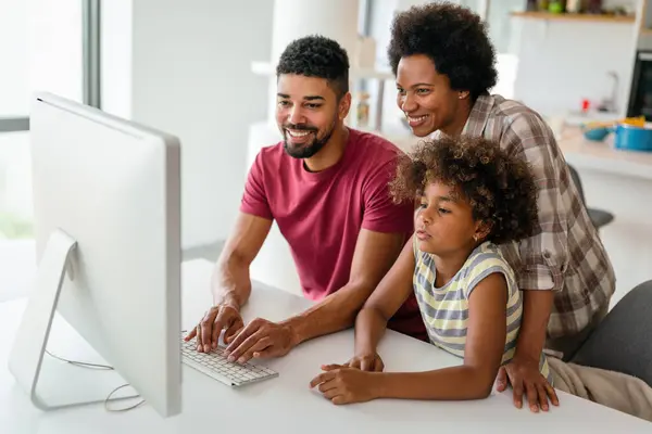 Smiling afro-american family working with a computer at home. Technology internet communication fun concept.