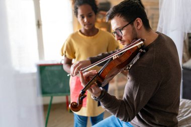 Müzik çok eğlenceli. Genç baba, evlatlık kızına keman çalmayı ve gülümsemeyi öğretiyor. Tek ebeveyn çocuk mutluluğu kavramı.