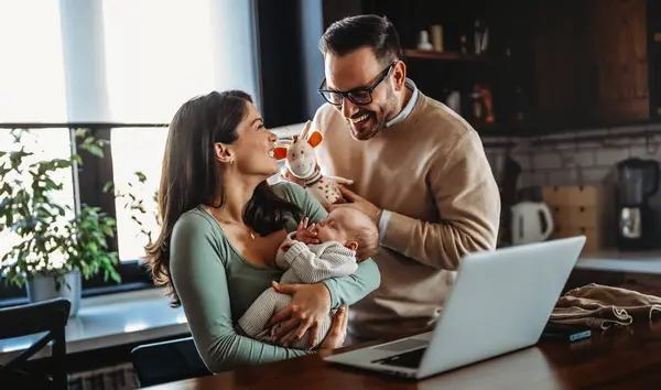 Happy young family with infant newborn baby having video call online conference conversation with relatives doctor pediatrician, having consultation remotely, communicating with friends