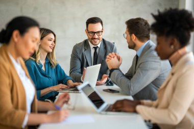 İşletme bürosundaki meslektaşlarıyla birlikte çalışırken analitik rapor sunan başarılı çoklu etnik çeşitlilikte iş adamları
