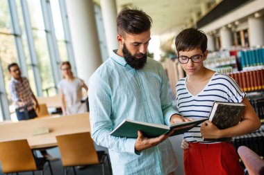 Eğitim kampüsü arkadaşlığı kavramı. Bir grup mutlu öğrenci üniversite kütüphanesinde birlikte öğreniyor.