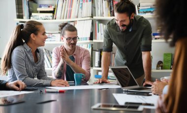 Mutlu iş arkadaşları, modern ofisteki iş arkadaşlarıyla iş başında ve toplantıdalar. Proje fikirlerini tartışmak veya strateji geliştirmek.