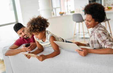 Teknolojik cihazlara takıntılı mutlu Afro-Amerikan genç ailesi dijital tablet, bilgisayar, akıllı telefonlar kullanıyor..