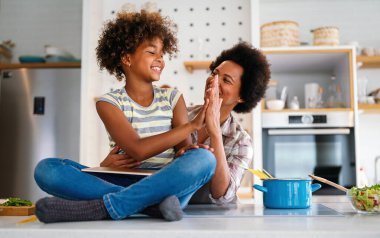 Eğitim, aile çevrimiçi öğrenme kavramı. Tablet bilgisayarlı Afrika kökenli anne ve kız evde ödev yapıyorlar.