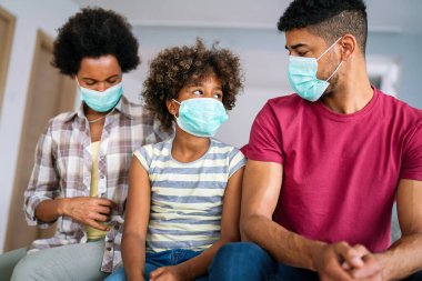 Ev karantinası sırasında maskeli genç Afro-Amerikan ailesi. Ailesi koronavirüs ve grip salgını sırasında maske takıyor. Virüs ve hastalık koruması, COVID