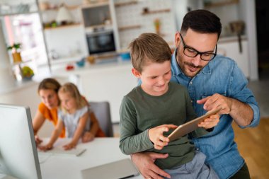 Uzaktan öğrenme, online eğitim, ev işi okulu konsepti. Evde dijital cihazları olan mutlu bir aile.