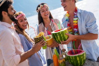 Mutlu gençler plaj partisinde eğleniyor. Bir grup arkadaş yaz tatilinin ve seyahatin tadını çıkarıyor