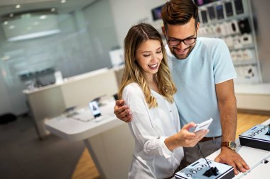 Teknoloji alışverişi dijital cihaz konsepti. Mobil dükkanından yeni bir akıllı telefon alan mutlu gençler.