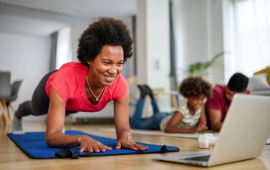 Geçmişinde ailesi olan Afrikalı Amerikalı bir kadın evde çalışıyor. Fitness ve sağlıklı yaşam tarzı konsepti.