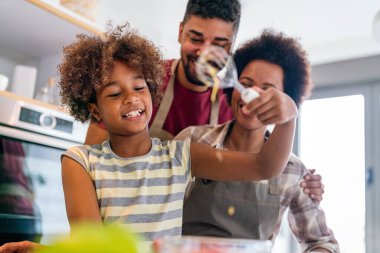Mutlu Afro-Amerikan ebeveynler ve çocuklar mutfakta sağlıklı yiyecekler hazırlarken eğleniyorlar. Aile mutluluğu eğlence konsepti