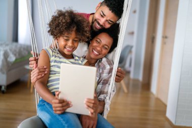 Mutlu Afro-Amerikan ailesi evde aletle eğleniyor. Siyah ebeveynler ve çocuklar dijital tablet kullanıyorlar