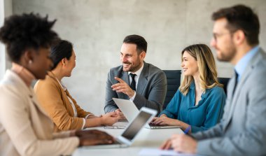 Çok ırklı başarılı iş adamları, analitik rapor sunan profesyoneller modern ofisteki meslektaşlarıyla birlikte çalışıyorlar.