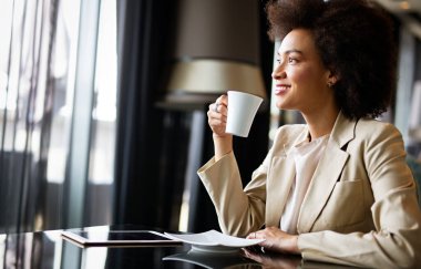 Kahve molası sırasında ofiste dijital tabletini kullanan zeki Afrikalı Amerikalı genç girişimci kadın portresi.