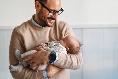 Yeni doğmuş bebeğini kucaklayan ve öpen bir babanın portresi. Erkek ebeveyn çocuğunu tutuyor. Otantik yaşam tarzı dokunaklı bir an. Bekar baba aile hayatı konsepti.