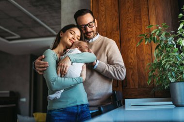 Barışçıl, genç, evli bir çift aile olmanın keyfini çıkarıyor, ebeveynler kucağında yeni doğmuş bir bebek, birbirlerine yakın duruyorlar. Ebeveynlik, doğum, ilişki kavramı