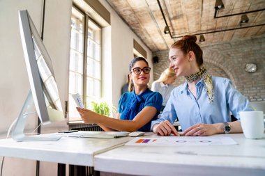 Yaratıcı ofiste birlikte çalışan başarılı iş kadınları. Birlikte çalışan kadın girişimciler gülümsüyor, bir takım olarak beyin fırtınası yapıyorlar..