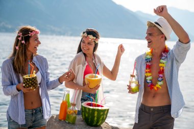 Mutlu gençler plaj partisinde eğleniyor. Bir grup arkadaş yaz tatilinin ve seyahatin tadını çıkarıyor