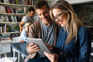 Çeşitli meslektaşları tablet kullanarak çevrimiçi projeyi tartışarak kapat. Gülümseyen iş kadını ve işadamı cihaz ekranına bakıyor, ofiste birlikte çalışıyorlar.