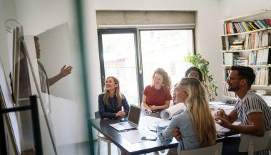 Gülümseyen çeşitli meslektaşlar toplantı odasında toplanmış mali istatistikleri tartışıyorlar. Mutlu çok ırklı iş arkadaşları ofis toplantılarında işbirliği yaparken eğleniyorlar. Takım çalışması konsepti.