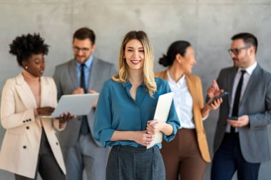 Modern ofiste yan yana sıralanmış, etnik çeşitlilikte gülümseyen iş arkadaşlarının portresi.