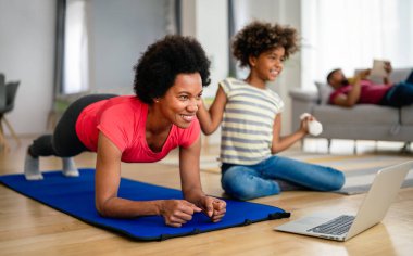 Mutlu genç anne ve kız yoga yapıyor, evde birlikte, spor minderinde oturuyor, sağlıklı yaşam tarzının tadını çıkarıyorlar.