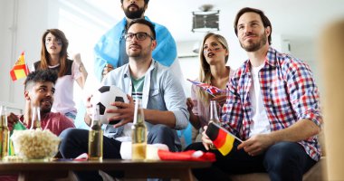 Bir grup mutlu arkadaş evde eğleniyor, maç izliyor ve birlikte eğleniyorlar.