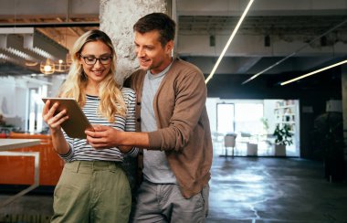 Genç iş adamları iş yerinde birlikte eğleniyor, takım çalışması yapıyor ve sohbet ediyorlar..