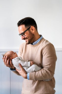 Sevgi dolu baba yeni doğmuş bebeğini evde taşıyor. Mutlu bir babanın parlak portresi. Elinde uyuyan bebeği tutuyor..
