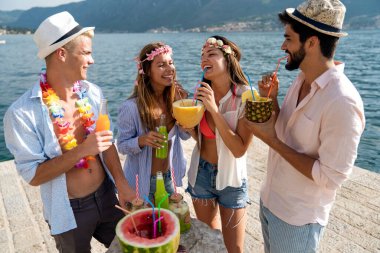 Mutlu gençler plaj partisinde eğleniyor. Bir grup arkadaş yaz tatilinin ve seyahatin tadını çıkarıyor