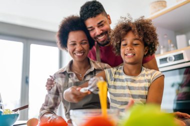 Mutlu Afro-Amerikan gülümseyen ailesi mutfakta sağlıklı yemekler hazırlıyor, hafta sonları birlikte eğleniyorlar.