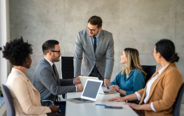 Çok ırklı başarılı iş adamları, analitik rapor sunan profesyoneller modern ofisteki meslektaşlarıyla birlikte çalışıyorlar.