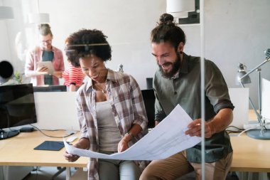 Genç iş adamları, mühendisler, yöneticiler modern ofiste yeni bir başlangıç projesi üzerinde çalışıyorlar. Belgeleri, planları analiz et. Takım çalışması tasarımı iş arkadaşı kavramı