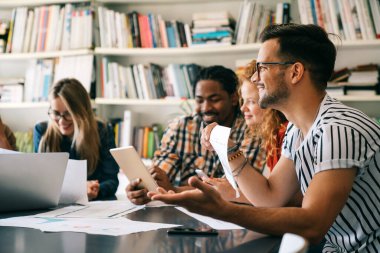 Gülümseyen çeşitli meslektaşlar toplantı odasında toplanmış mali istatistikleri tartışıyorlar. Mutlu çok ırklı iş arkadaşları ofis toplantılarında işbirliği yaparken eğleniyorlar. Takım çalışması konsepti.